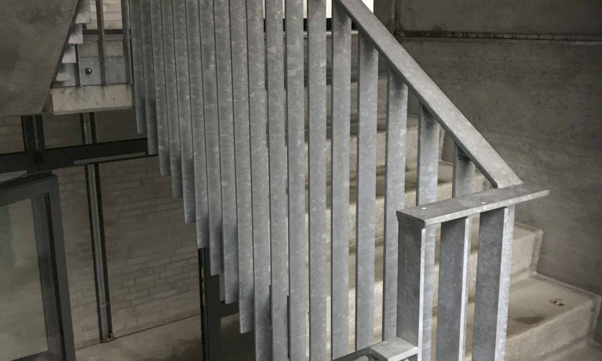 Domicil betontrappe med gelænder i fladstål set inde fra opgangen