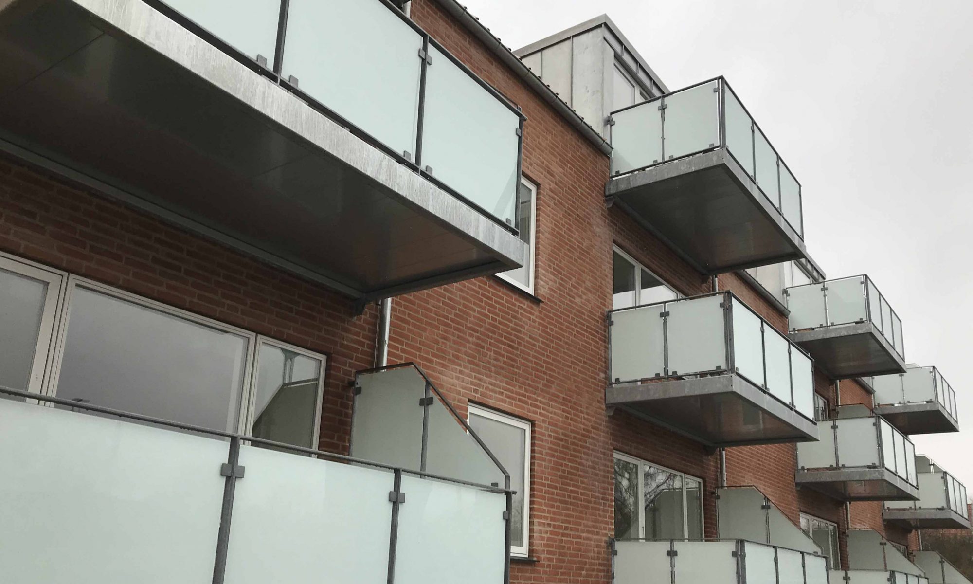 Dette er et billede af 12 galvaniserede altaner med glasudfyldning.